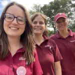 Photo of Thames Basin Heaths Wardens Kay, Sophie and Hannah smiling to camera. They are wearing logo'd burgundy uniform tshirts